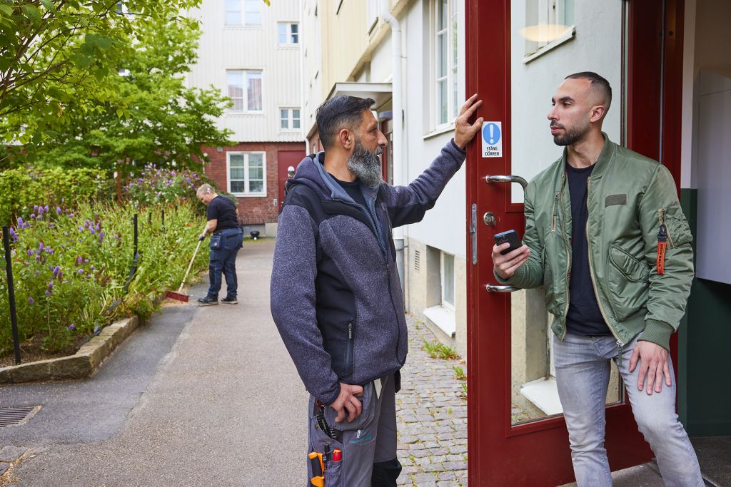 Husvärd pratar med hyresgäst på gården.